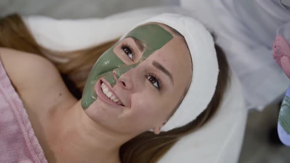 Healthy Girl Lying with Mask of Green Clay on Face and Relaxes During Treatment alt