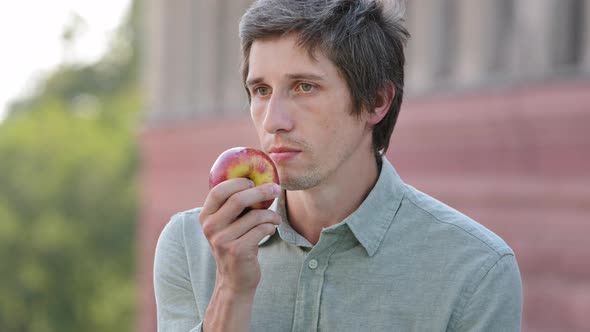Young Attractive Cheerful Man Holding Apple in Hand Sniffing Ripe Fruit Discovers Absence of Smell alt
