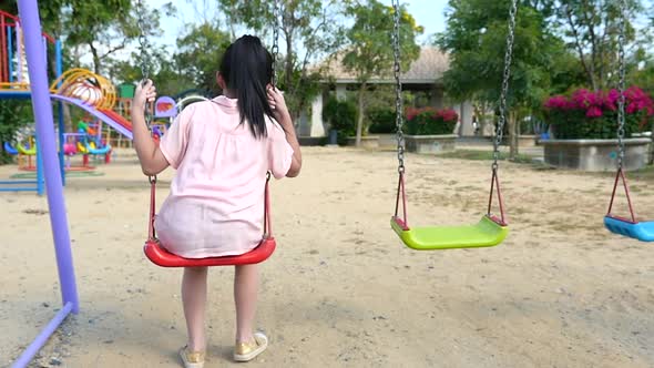 Sad Asian Girl Playing Swing In The Park alt