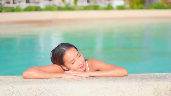 Young asian woman enjoy around outdoor swimming pool for leisure alt