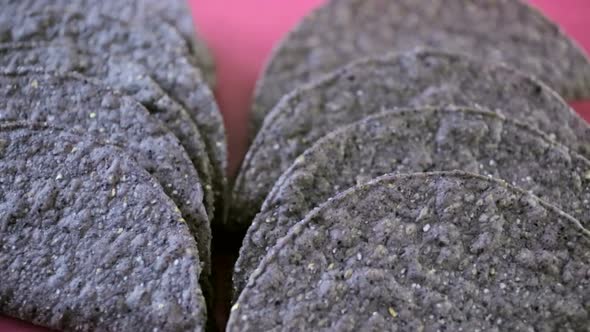 Blue corn taco shells on a pink background. alt