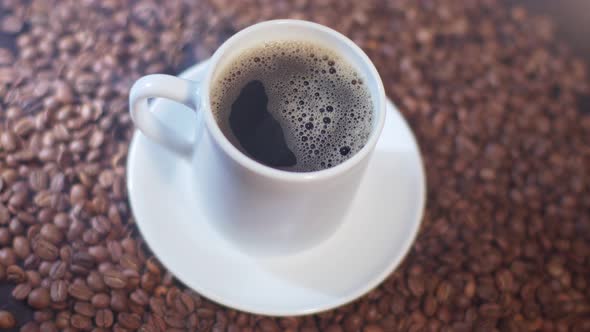 Closeup View of a Coffee Mug with Light Roasted Beans Around It alt