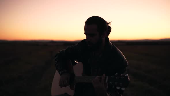 Man playing guitar in a meadow alt