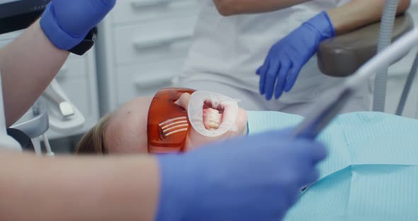 A Woman Patient in Protective Glasses with a Spreader Over Her Mouth alt