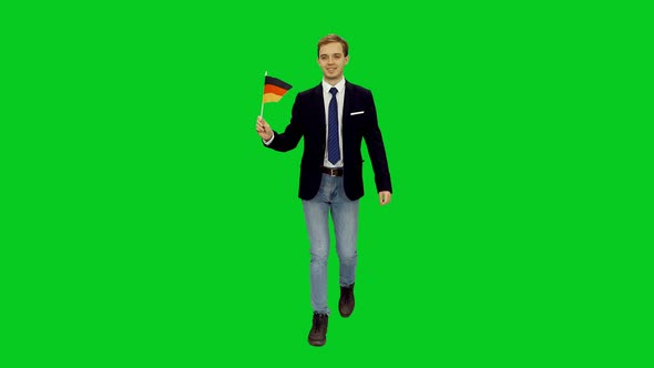 Young Friendly Businessman Walks with Waving Flag of Germany on Green Screen