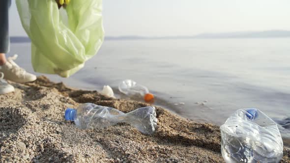 A Volunteer Puts Empty Plastic Bottles Dirty Napkins and Used Papers in a Garbage Bag alt
