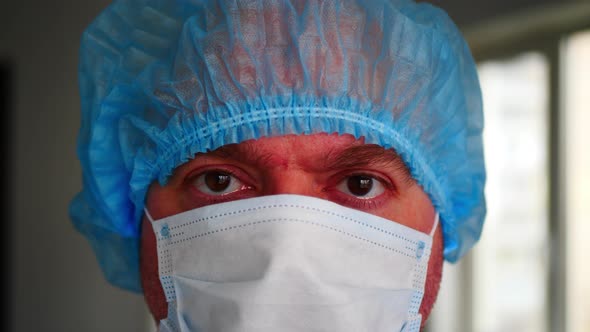 Tired professional doctor in medical surgical disposable face mask. Slow motion