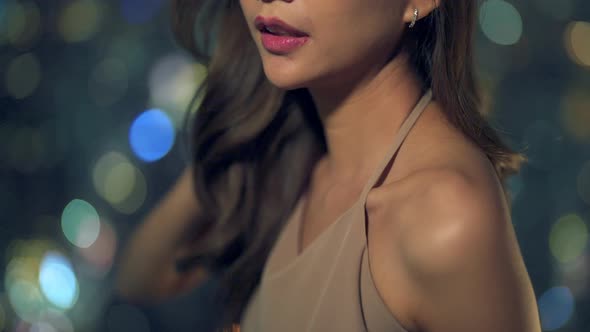 4K Portrait of Asian woman standing by the window at skyscraper at night. alt