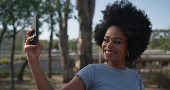 Mixed race woman taking pictures in park alt