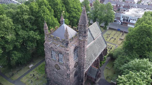 Aerial view above rural English town countryside idyllic church bell tower and graveyard alt