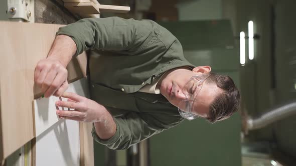 Confident Carpenter Working with Equipment on Wooden Table in Carpentry Shop