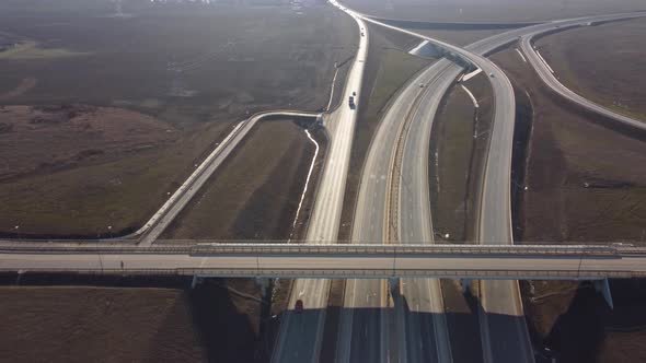 Aerial drone view flight Over road bridge, car junction with driving cars and trucks on sunny day.