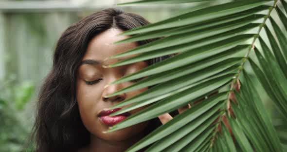 Beautiful Girl African American with Tanned Skin Poses and Walks Among Tropical alt