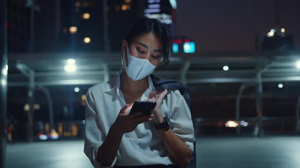 Asia businesswoman in fashion clothes wearing face mask using smart phone typing text message.