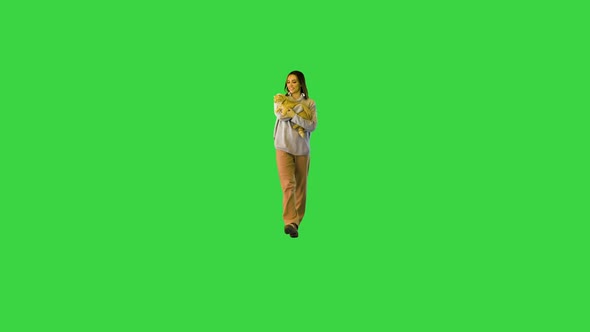 Girl Walking Towards Camera and Holding a Cat on a Green Screen Chroma Key