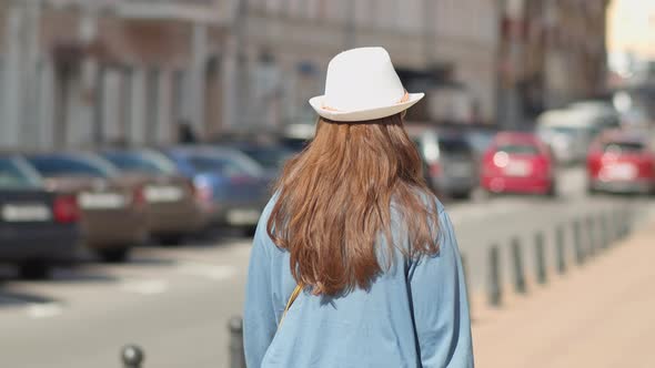 Happy Brunette Woman Travels Around the City Back View Woman in Hat Walking Through the City