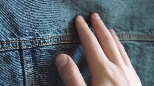 A Man's Hand Touches Blue Denim Checking Its Quality Before Buying in an Outlet Clothing Store