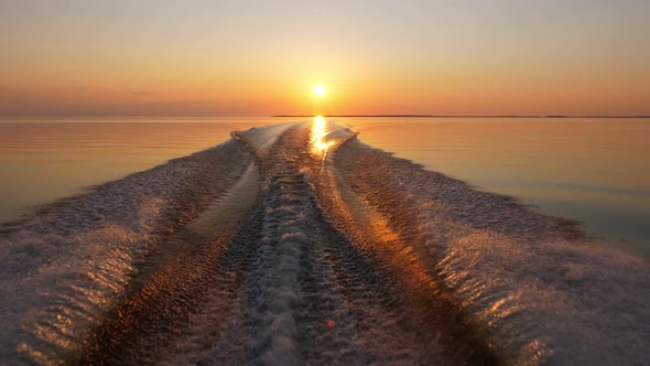 Look back to sunset from speedboat running fast at calm lake