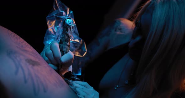 Close up of a young female tattoo artist working in a tattoo studio.BMPCC 4K alt