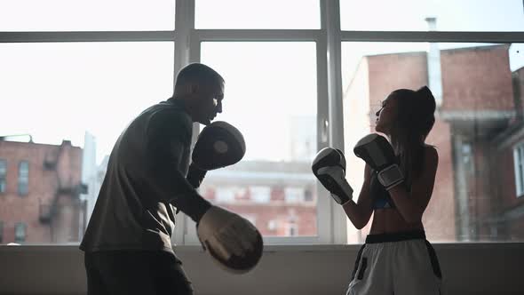A Young Girl Conducts Kickboxing Training and Practices Paw Strikes with a Professional Boxer alt