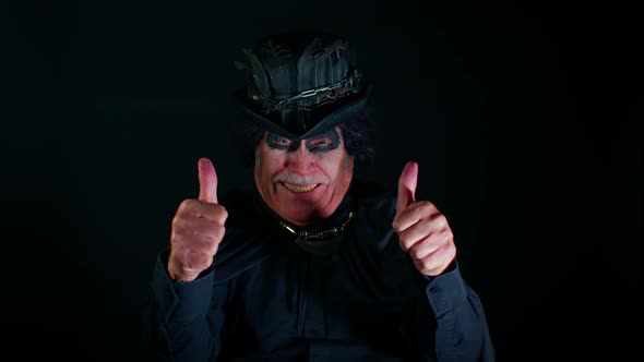 Sinister Elderly Man with Scary Halloween Witcher Makeup in Costume Raises Thumbs Up Like Gesture alt
