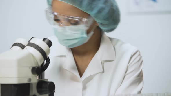 Science Project, Lab Researcher Wearing Latex Gloves and Working on Microscope alt