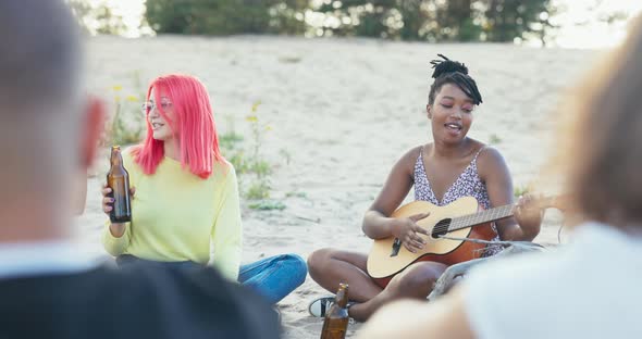 A Woman of AfricanAmerican Beauty Has Her Hair Tied Up in a Bun Plays Guitar for Her Friends People alt