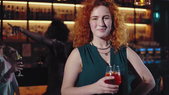 Redheaded woman toasting in a cocktail bar