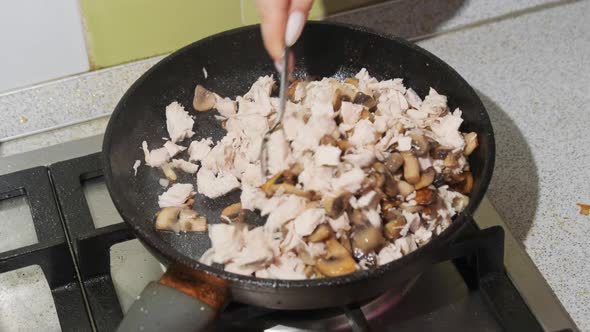 Women Hand Mixes Sauteed Mushrooms in a Pan at Home Kitchen Cooking Julienne alt