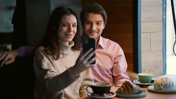 A Young Attractive Couple Communicates Through a Video Call with Friends in a Cafe