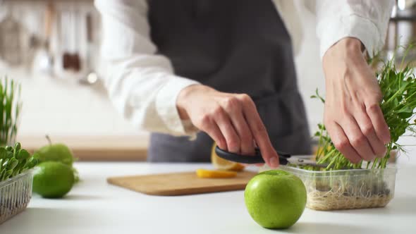 Cooking A Vegan Lunch. A Woman In An Apron Cuts Green Pea Sprouts. Healthy Eating From Food. Cooking alt