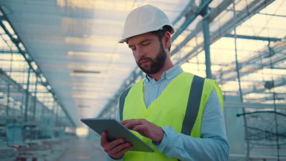 Factory Worker with Tablet Inspecting New Manufacture Wearing Green Uniform alt