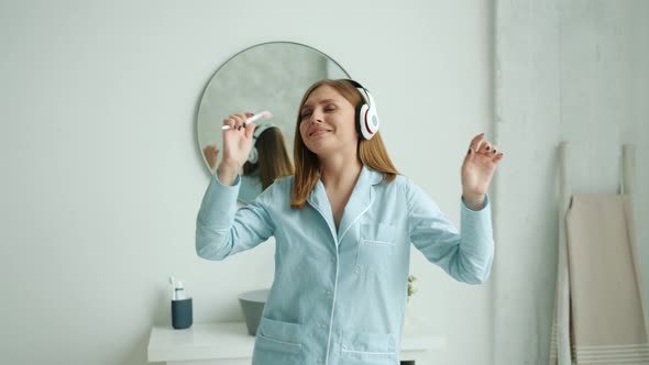 Slow Motion of Happy Woman in Headphones Brushing Teeth Dancing in Bathroom alt