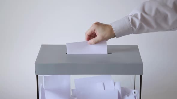 Voter Lowers The Ballot In A Transparent Ballot Box