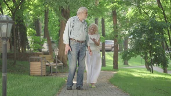 Happy Date of Positive Senior Caucasian Couple in Sunny Summer Park. Smiling Old Man Waiting for alt