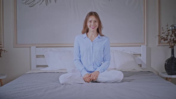 Attractive Female Wearing Pajamas Sits in Bedroom