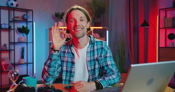 Man Gesturing Ok Into Camera in Beautifully Decorated Room with Night Lighting alt