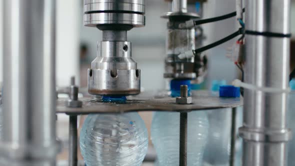 Water Factory Industrial Machine Puts Caps on Plastic PET Bottles with Water Close Up