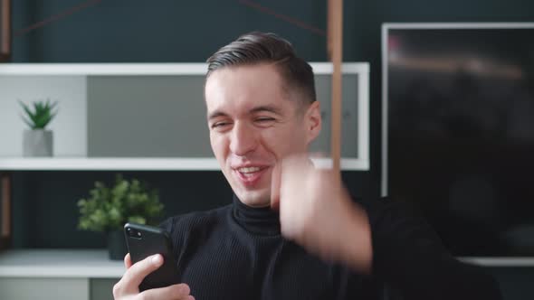 Happy Young Man Winner Celebrating Success Looking at Smartphone