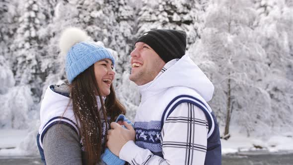 Happy Family Couple Travelers Enjoying Winter Nature Near a Mountain River alt