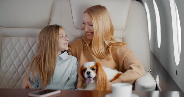Mature Mother and Preteen Daughter Travelling on Personal Jet with Dog alt