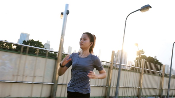 Female young Asian athlete running on the street in the city.