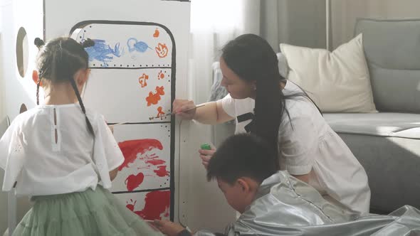 An Asian Female with Kids Play in the Living Room at Home a Boy in an Astronaut Costume Sitting on alt