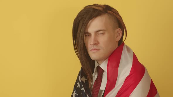 Young Man Wrapped in American Flag on Yellow Background alt
