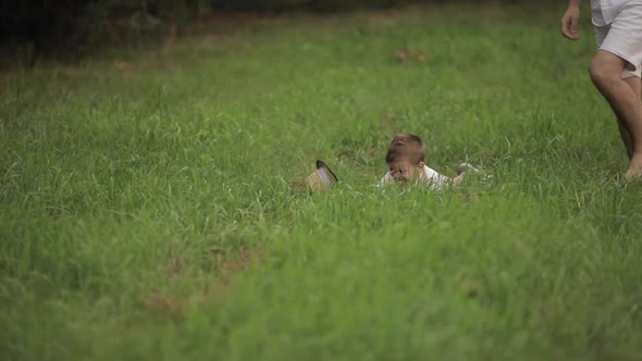 Dad Plays with His Son in the Garden, the Child Falls, but Continues To Laugh