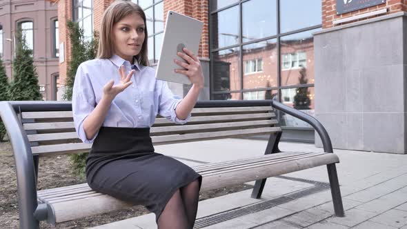 Online Video Chat on Tablet by Woman Sitting Outside Office alt
