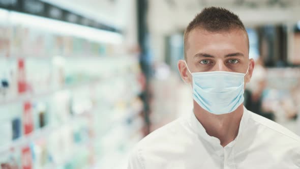 Portrait of Young Serious Man in Medical Mask of Sales Assistant at Pharmacy alt