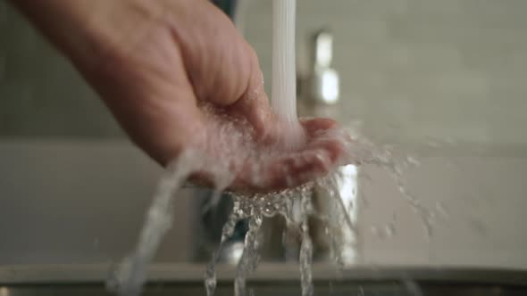 Man Hand is Checking the Temperature of Water Coming Out of the Faucet