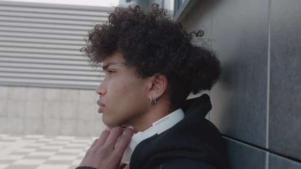 Video of Relaxed Afroamerican Young Man Listening to Music with Headphones Leaning on Stone Wall at alt