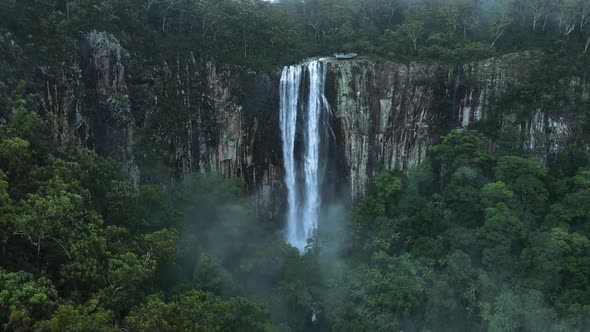A majestic waterfall cascading over a lush tropical rainforest mountain scenery. Panoramic high dron alt